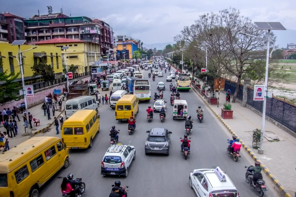 Street scene in Kathmandu, Nepal with yellow minibuses and other traffic.